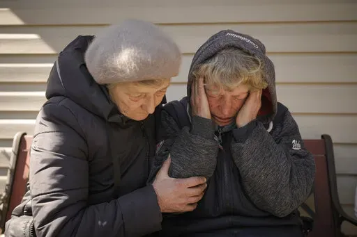 A neighbor comforts Natalia Vlasenko, whose husband, Pavlo Vlasenko, and grandson, Dmytro Chaplyhin, called Dima, were killed by Russian forces, as she cries in her garden in Bucha, Ukraine, Monday, April 4, 2022. Russian soldiers picked up Dima during a March 4 sweep, accused him of being a spotter helping the Ukrainian military. Asked “What would justice be for you?,” the grandmother of 20-year-old Dima says, “I- I- I can’t even- I don’t know. These scoundrels…” (AP Photo/Vadim G