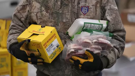 A Utah Food Bank volunteer carries groceries for the needy at a mobile food pantry distribution site Wednesday, Dec. 21, 2022, in Salt Lake City. The end of the calendar year is when nonprofits make appeals far and wide to attract donors — in part because of holiday traditions or, for some, tax advantages. (AP Photo/Rick Bowmer, File)