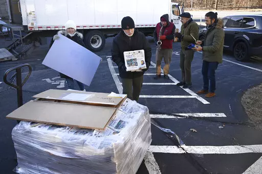 Andy Thibault, Editor and Publisher of The Winsted Citizen, carries the first bundle of papers off a pallet as Advertising and Circulation Director Rosemary Scanlon holds the first print press plate while a group of musicians play behind them after the arrival of the first delivery of the paper on, Friday, Feb. 3, 2023, in Winsted, Conn. At a time that local newspapers are dying at an alarming rate, longtime activist Ralph Nader is helping give birth to one. Nader put up $15,000 to help launch T