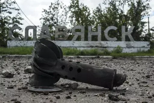 A part of the mortar shell is seen in front of a sign that reads 'Slovyansk', after heavy fighting between pro-Russian fighters and Ukrainian government troops just outside Slovyansk, eastern Ukraine, Wednesday, July 9, 2014. The eastern Ukrainian city of Slovyansk was occupied by pro-Russian separatists for months in 2014. Now its people are preparing to defend their community again as the fighting draws closer and invites a major battle. Slovyansk is a city of splintered loyalties, with some r