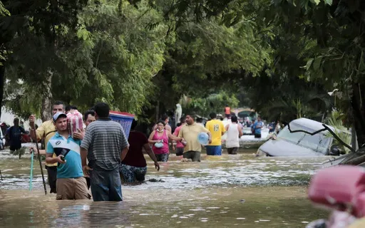Residents walk past inundated vehicles in the flooded streets of Planeta, Honduras, Nov. 6, 2020, in the aftermath of Hurricane Eta. (AP Photo/Delmer Martinez, File)