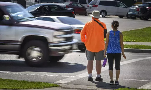 In this June 8, 2016, file photo, a maroon and silver truck drove, left, drives through the marked crosswalk in front of pedestrian volunteers Dave Passiuk and Nelsie Yang in St. Paul, Minn. Drivers of bigger vehicles such as pickup trucks and SUVs are more likely to hit pedestrians while making turns than drivers of cars, according to a new study. The research released Thursday, March 17, 2022, by the Insurance Institute for Highway Safety points to the increasing popularity of larger vehicles 