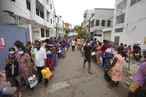 Sri Lankans queue up near a fuel station to buy kerosene in Colombo, Sri Lanka, Tuesday, April 12, 2022. When the Federal Reserve raises interest rates -- as it did Wednesday, May 4, 2022 -- the impact doesn’t stop with U.S. homebuyers paying more for mortgages or Main Street business owners facing costlier bank loans. The fallout can be felt beyond America’s borders, hitting shopkeepers in Sri Lanka, farmers in Mozambique and families in poorer countries around the world. (AP Photo/Eranga J