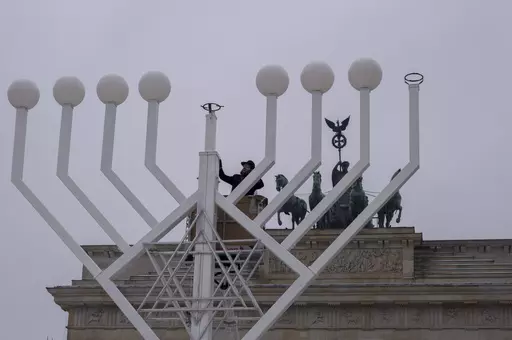 Rabbi Yehuda Teichtal, center, inspects a giant Hanukkah Menorah, set up by the Jewish Chabad Educational Center ahead of the Jewish Hanukkah holiday, in front of the Brandenburg Gate at the Pariser Platz in central Berlin, Germany, Wednesday, Dec. 6, 2023. Holocaust survivors from around the globe will mark the start of the fifth day of Hanukkah together with a virtual ceremony as worries grow among Jews worldwide about the Israel-Hamas war and a spike of antisemitism in Europe, the United Stat