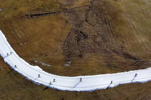 People ski on a cross country slope in Ramsau, Austria, Friday, Jan. 6, 2023. Sparse snowfall and unseasonably warm weather in much of Europe is allowing green grass to blanket many mountaintops across the region where snow might normally be. (AP Photo/Matthias Schrader, File)