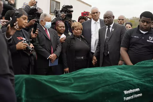 Civil rights attorney Ben Crump, center right, Bettersten Wade, center, mother of Dexter Wade, a 37-year-old man who died after being hit by a Jackson, Miss., police SUV driven by an off-duty officer, watches her son's body transferred to a mortuary transport after being exhumed from a pauper's cemetery near the Hinds County Penal Farm in Raymond, Monday, Nov. 13, 2023. After men in near Mississippi's capital were buried in a pauper’s cemetery without their relatives’ knowledge, the U.S. Jus