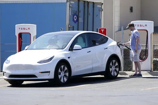 A Tesla owner charges his vehicle at a charging station in Topeka, Kan., Monday, April 5, 2021.  Tesla reported 273 crashes involving partially automated driving systems, according to statistics released by U.S. safety regulators on Wednesday, June 15, 2022. But the National Highway Traffic Safety Administration cautioned against using the numbers to compare automakers, saying it didn’t weigh them by the number of vehicles from each manufacturer that use the systems, or how many miles those ve