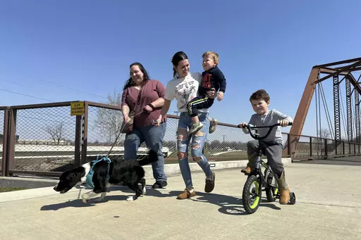 From left; Emerson Howard and dog Dixie enjoy a walk along with Destiny Porter and her children, 2-year old Merrick Mercer and 4-year old Maxton Mercer at the Kitselman bridge connecting the Cardinal and White River Greenway trails in Muncie, Ind., Wednesday, March 13, 2024. The Cardinal Greenways pathway born from eastern Indiana's abandoned railroad tracks will become a central cog in the Great American Rail Trail — a planned 3,700-mile network of uninterrupted trails spanning from Washingto