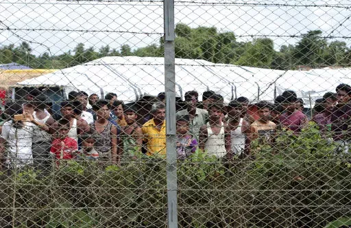 Rohingya refugees gather near a fence during a government organized media tour, to a no-man's land between Myanmar and Bangladesh, near Taungpyolatyar village, Maung Daw, northern Rakhine State, Myanmar, June 29, 2018. An international case accusing Myanmar of genocide against the Rohingya ethnic minority returns to the United Nations' highest court Monday, Feb. 21, 2022, amid questions over whether the country's military rulers should even be allowed to represent the Southeast Asian nation. (AP