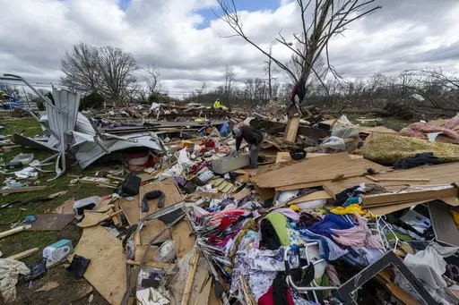 People walk through damage from a late-night tornado in Sullivan, Ind., April 1, 2023. (AP Photo/Doug McSchooler, File)