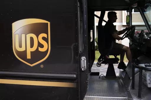 United Parcel Service driver Hudson de Almeida steers through a neighborhood while delivering packages, June 30, 2023, in Haverhill, Mass. The union representing 340,000 UPS workers said Tuesday, Aug. 22, that its members voted to approve the tentative contract agreement reached last month, putting a final seal on contentious labor negotiations that threatened to disrupt package deliveries for millions of businesses and households nationwide. (AP Photo/Charles Krupa, File)