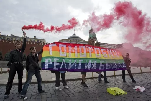 Gay rights activists hold a banner reading "Homophobia - the religion of bullies" during their action in protest at homophobia, on Red Square in Moscow, Russia, on July 14, 2013. Russian lawmakers have approved a toughened version of a bill that outlaws gender transitioning procedures, with added clauses that mandate annulling marriages in which one person has "changed gender" and barring transgender people from becoming foster or adoptive parents. (AP Photo/Evgeny Feldman, File)