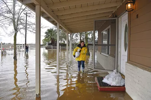 Stephanie Beard, of Brentwood, carries a sand bag to her flooded home on Bixler Road in Brentwood, Calif., on Monday, Jan. 16, 2023. The last in a three-week series of major winter storms is churning through California. (Jose Carlos Fajardo/Bay Area News Group via AP)