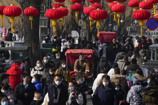 A trishaw driver wades through a crowded street at the frozen Houhai Lake in Beijing, Monday, Jan. 30, 2023. The outlook for the global economy is growing slightly brighter as China eases its zero-COVID policies and the world shows surprising resilience in the face of high inflation, elevated interest rates and Russia's ongoing war against Ukraine.(AP Photo/Andy Wong)