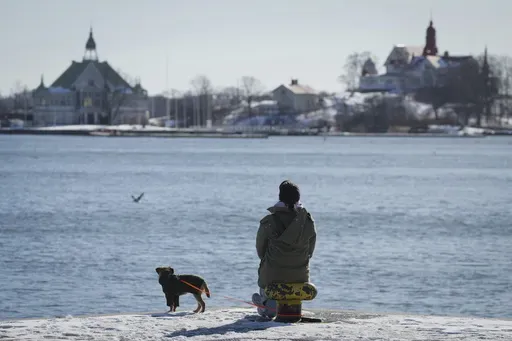 A woman enjoys a sunny and frosty day on the embankment of the South Harbour in Helsinki, Finland, Saturday, March 15, 2025. (AP Photo/Sergei Grits)