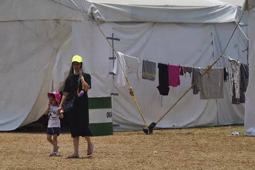 A Ukrainian refugee walks with her child at a camp in Utopia Park in Iztapalapa, Mexico City, Monday, May 2, 2022. (AP Photo/Marco Ugarte)