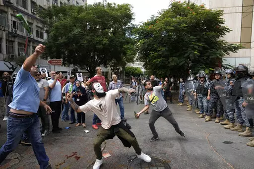 Protesters throw bottles glasses at the Lebanese Central Bank building, background, where the anti-government demonstrators rally against the Lebanese Central Bank Governor Riad Salameh and the deepening financial crisis, in Beirut, Lebanon, Wednesday, Oct. 5, 2022. Lebanon's once burgeoning banking sector has been hard hit by the country's historic economic meltdown, suffering staggering losses worth tens of billions of dollars and leaving the future of the small nation's lenders unknown betwee