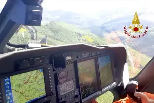 A Italian firefighter helicopter searches the site of a helicopter crash in central Italy, Saturday, June 11, 2022. Italian rescuers say they have located the scorched crash site of a helicopter carrying seven people that went down in north-central Italy during a storm. News reports say five bodies were located. Italy’s Alpine rescue service said ground crews were already on the scene on Mt. Cusna, after a hiker reportedly came across remnants of the chopper. (Vigili del Fuoco via AP)