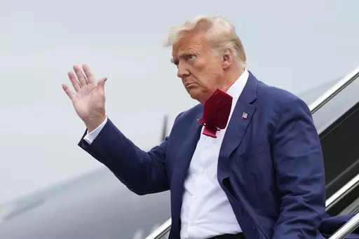 Former President Donald Trump waves as he steps off his plane at Ronald Reagan Washington National Airport, Aug. 3, 2023, in Arlington, Va. A slim majority of Americans approve of the U.S. Justice Department indicting Trump over his efforts to remain in office after losing the 2020 election, according to a new poll from The Associated Press-NORC Center for Public Affairs Research. (AP Photo/Alex Brandon, File)