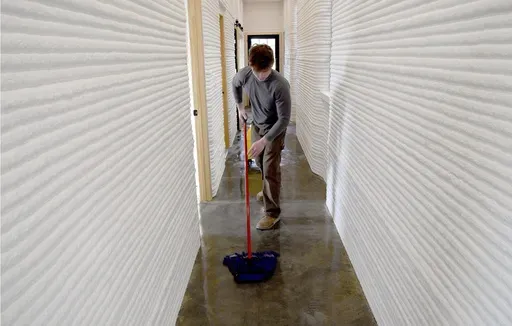 David Leach mops the floor of a 3D-printed concrete home built by VeroTouch in Buena Vista, Colo., on Feb. 19, 2025. (AP Photo/Thomas Peipert)