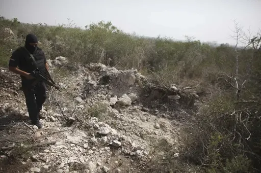 An officer walks past a hole that police say was used as a mass grave, near San Fernando, Tamaulipas state, Mexico, April 27, 2011. The body of 17-year-old Guatemalan Yovanny was found among nearly 200 others in clandestine gravesites, discovered in April and May 2011 near San Fernando. (AP Photo/Alexandre Meneghini, File)