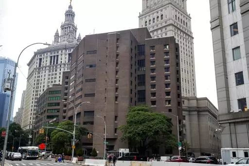 The brown bricked Metropolitan Correctional Center is shown in the foreground with municipal and court facilities in the background, Aug. 13, 2019, in New York. A federal correctional officer was arrested Friday, March 18, 2022, for lying to investigators after a loaded gun was found in an inmate's cell at the federal jail — the same lockup where Jeffrey Epstein killed himself in 2019. (AP Photo/Mary Altaffer, File)