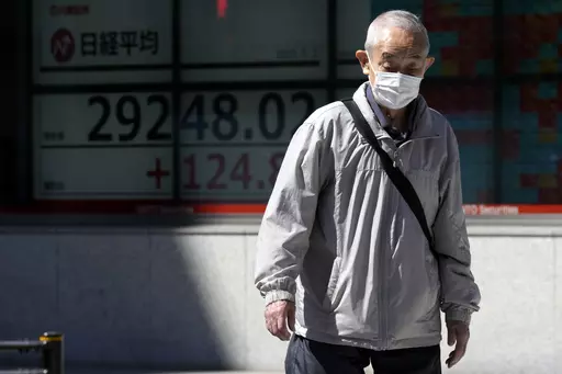 A person walks past an electronic stock board showing Japan's Nikkei 225 index at a securities firm Tuesday, May 2, 2023, in Tokyo. Asian shares were mixed Tuesday with some markets closed or anticipating holidays and investors showing muted reaction to the latest historic U.S. banking failure. (AP Photo/Eugene Hoshiko)