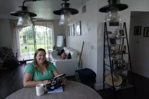 Melissa Lombana, 43, a high school teacher and mountain bike enthusiast, poses for a picture while working online, in her one-bedroom apartment in Miramar, Fla., Wednesday, July 26, 2023. Lombana's rent has increased each of the last two years and now amounts to nearly half her monthly income. "In a year, I will not be able to afford living here at all," she said. (AP Photo/Rebecca Blackwell)