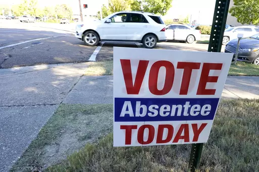 A sign encouraging people to vote absentee stands outside the Hinds County Courthouse in Jackson, Miss., Tuesday, Oct. 6, 2020. The 2023 general election absentee ballots in a different part of Mississippi, Jones County, will be several days late because a candidate dropped out of a race on Thursday, Sept. 21, 2023, and the ballot there had to be redone after a substitute candidate was named, according to Circuit Clerk Concetta Brooks. (AP Photo/Rogelio V. Solis, File)