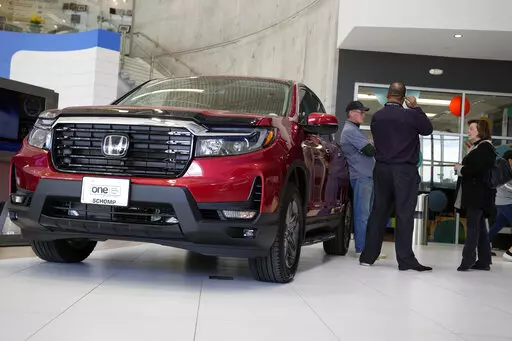 Customers confer with a salesperson as a 2022 Ridgeline pickup truck sits on the showroom floor of a Honda dealership, Friday, April 15, 2022, in Highlands Ranch, Colo. (AP Photo/David Zalubowski, File)