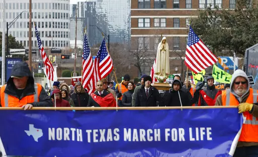 Protesters walk along Jackson St. during the North Texas March for Life, celebrating the passage and court rulings upholding the Texas law known as Senate Bill 8, on Saturday, Jan. 15, 2022, in Dallas. Abortions in Texas fell by 60% in the first month under the most restrictive abortion law in the U.S. in decades. That's according to the fist figures released by Texas health officials since the law known as Senate Bill 8 took effect in September. (Shafkat Anowar/The Dallas Morning News via AP)