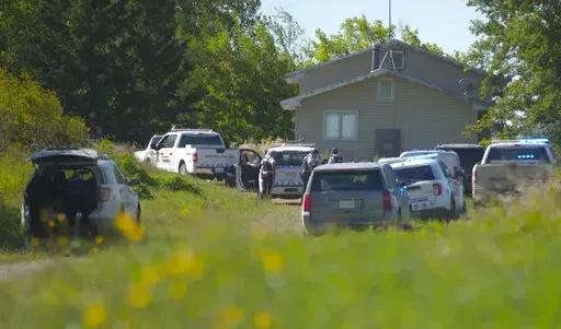 In this image taken from video, Canadian law enforcement personnel surrounded a residence on the James Smith Cree First Nation reservation in Saskatchewan, Canada, Tuesday, Sept. 6, 2022, as they search for a suspect in a series of stabbings. (AP Photo/Robert Bumsted)