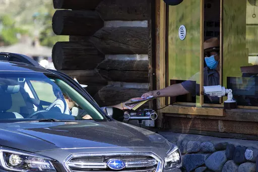 In this Monday, June 1, 2020 photo, a gate attendant at the North Entrance deals with visitors as the Montana entrances to Yellowstone National Park, in Wyoming, reopened after being closed due to COVID-19. On Friday, Dec. 23, 2022, The Associated Press reported on stories circulating online incorrectly claiming Yellowstone National Park officials have “closed down the park” due to a rising “volcanic uplift.” (Ryan Berry/Bozeman Daily Chronicle via AP, File)/Bozeman Daily Chronicle via A