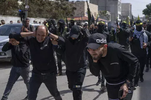 Palestinian gunmen shoot in the air during the funerals for Sanad Abu Atiyeh, 17 and Yazid al-Saadi, 23, in the West Bank refugee camp of Jenin, Jenin, Thursday, March 31, 2022. Israeli forces raided a refugee camp in the occupied West Bank early Thursday, setting off a gun battle in which two Palestinians were killed and 15 were wounded, the Palestinian Health Ministry said. (AP Photo/Nasser Nasser)