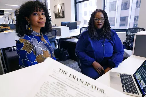 Amber Payne, left, and Deborah Douglas co-editors-in-chief of the new online publication of "The Emancipator" pose at their office inside the Boston Globe, Wednesday, Feb. 2, 2022, in Boston. Boston University's Center for Antiracist Research and The Boston Globe's Opinion team are collaborating to resurrect and reimagine The Emancipator, the first abolitionist newspaper in the United States, which was founded more than 200 years ago. The new incarnation of The Emancipator will explore ways to r