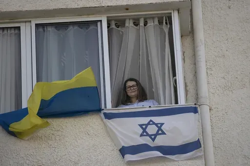 Tatyana Prima, who fled Mariupol, Ukraine, poses for a portrait with her national flag and the Israeli flag she displays outside of her apartment window in Ashkelon, southern Israel, Wednesday, Nov. 8, 2023. She thought she'd left the bombs behind when she fled after Russian troops decimated her city. Risking her life, the 38-year-old escaped with her injured husband and young daughter, bringing the family to safety in southern Israel. Yet the calm she was slowly regaining shattered on Oct. 7, w