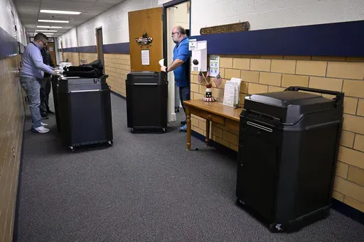 Christopher Prue, president of the Registrars of Voters Association of Connecticut, right, moves new voting tabulators out of his office at the Registrars of Voters to be redistributed to other towns, Thursday, March 27, 2025, in Vernon, Conn. (AP Photo/Jessica Hill)