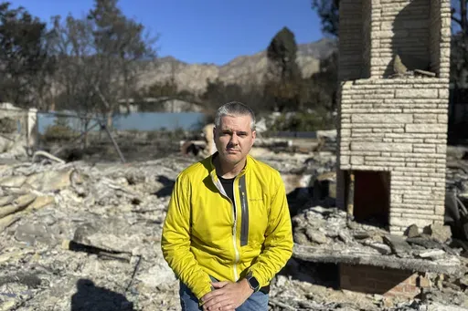 Ryan Pearson, a Los Angeles-based entertainment video editor for The Associated Press, sits in front of his home that was destroyed by the Eaton Fire, Wednesday, Jan. 15, 2025, in Altadena, Calif. (AP Photo/Ryan Pearson)