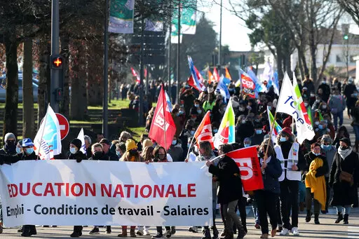 Teachers and students hold a banner reading " National Education- working condition - wages " as they demonstrate in Bayonne, southwestern France, Thursday, Jan. 13, 2022. French teachers have walked out in a nationwide strike Thursday to express anger at the way the government is handling the virus situation in schools, denouncing confusing rules and calling for more protection. (AP Photo/Bob Edme)