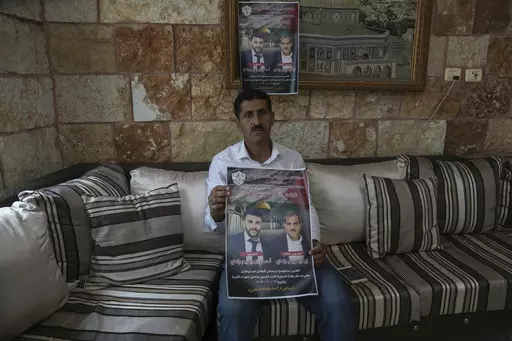 Abdelazim Wadi, 50, holds up a poster commemorating his brother, Ibrahim Wadi, and his nephew, Ahmed Wadi, who were killed by Israeli settlers during a funeral procession on Oct. 12 in the rural Palestinian village of Qusra, West Bank, Sunday, Nov. 12, 2023. With the world’s attention focused on the fighting in Gaza, Israeli settler violence against Palestinians since Oct. 7 has surged to the highest levels ever recorded by the United Nations. Palestinians say this Israel-Hamas war has left th