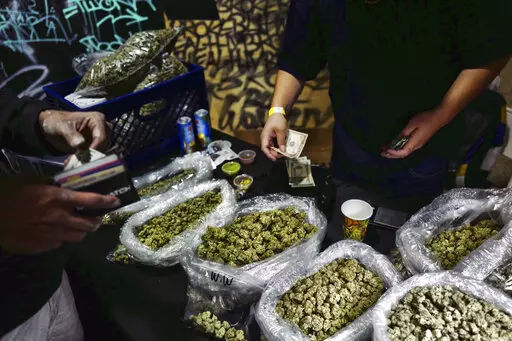 In this April 15, 2019, file photo, a vendor makes change for a marijuana customer at a cannabis marketplace in Los Angeles. An unwelcome trend is emerging in California, as the nation's most populous state enters its fifth year of broad legal marijuana sales. Industry experts say a growing number of license holders are secretly operating in the illegal market — working both sides of the economy to make ends meet. (AP Photo/Richard Vogel, File)