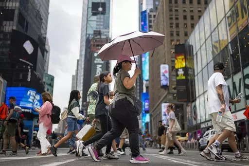 A pedestrian uses an umbrella to shield against the sun while passing through Times Square as temperatures rise, July 27, 2023, in New York. At about summer's halfway point, the record-breaking heat and weather extremes are both unprecedented and unsurprising, hellish yet boring in some ways, scientists say. (AP Photo/John Minchillo, File)