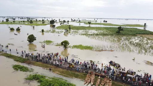 People walk through floodwaters with flooded farmlands forground after heavy rainfall in Hadeja, Nigeria, Sept 19, 2022. West and Central African countries are battling deadly floods that have upended lives and livelihoods, raising fears of further disruption of food supplies in many areas battling armed conflict. “Above-average rainfall and devastating flooding” have affected 5 million people this year in 19 countries across West and Central Africa, according to a new U.N. World Food Progra