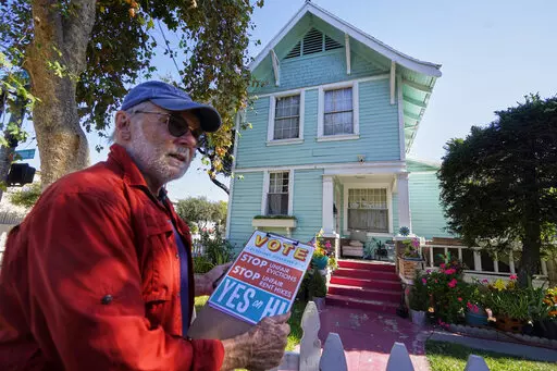 Yes on Measure H! volunteer Ed Washatka canvases the neighborhood in Pasadena, Calif., Saturday, Oct. 29, 2022. Cities across the country are pushing measures to stabilize or control rents when housing prices are skyrocketing. Voters from Orange County, Florida, and in several California cities are asking voters to approve ballot measures that would cap rent increases. (AP Photo/Damian Dovarganes)