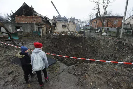 Children look at a crater created by an explosion in a residential area after Russian shelling in Solonka, Lviv region, Ukraine, Wednesday, Nov. 16, 2022. (AP Photo/Mykola Tys)