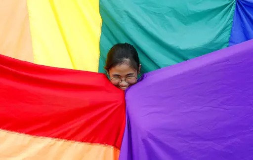 A supporter of the Philippine LGBT (Lesbians Gays Bisexual Transgender) group poses before the rainbow flag during the annual celebration of "Pride March" June 30, 2018, in Marikina city, east of Manila, Philippines. Singapore’s announcement Sunday, Aug. 22, 2022, that it would decriminalize sex between men is being hailed as a step in the right direction for LGBTQ rights in the Asia-Pacific region, a vast area of nearly 5 billion people with different laws and attitudes. (AP Photo/Bullit Marq