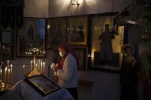 A woman attends a Christmas mass at an Orthodox Church in Bobrytsia, outskirts of Kyiv, Ukraine, Sunday, Dec. 25, 2022. Sunday began with the sound of sirens, but that didn't prevent people from gathering in the church and attend for the first time a Christmas mass on Dec. 25. (AP Photo/Felipe Dana)