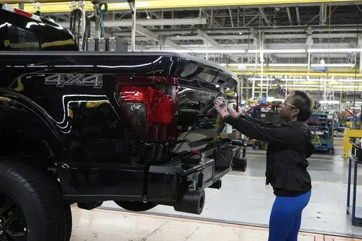 Assembly line worker Lashunta Harris applies the Ford logo on a 2024 Ford F-150 truck being assembled at the Dearborn Truck Plant, April 11, 2024, in Dearborn, Mich. On Friday, June 5, 2024, the U.S. government issues its June jobs report. (AP Photo/Carlos Osorio, File)