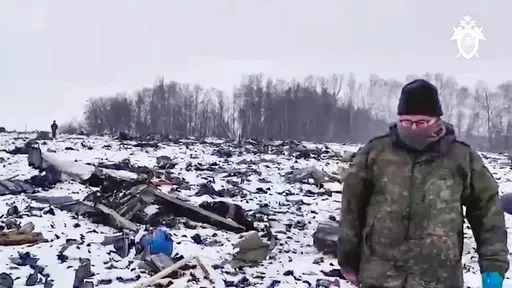 In this photo taken from video released by Russian Investigative Committee on Friday, Jan. 26, 2024, Russian Investigative Committee employee walks in a place with wreckage of the Russian military Il-76 plane crashed area near Yablonovo, Belgorod region of Russia, Thursday, Jan. 25, 2024. (Russian Investigative Committee via AP)