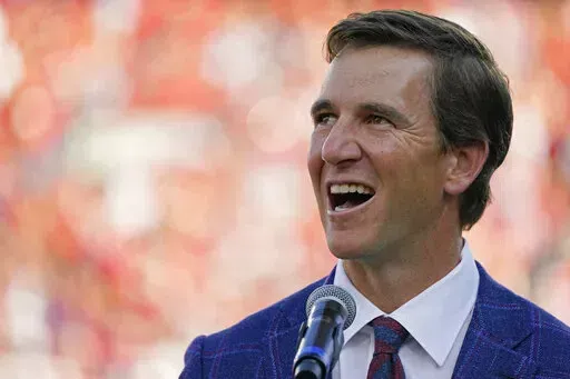 Former Mississippi quarterback Eli Manning laughs as he addresses the crowd as his jersey, number 10, is retired at a half time ceremony during an NCAA college football game against LSU in Oxford, Miss., Saturday, Oct. 23, 2021. The two-time Super Bowl MVP is already quite the media pro. (AP Photo/Rogelio V. Solis, File)